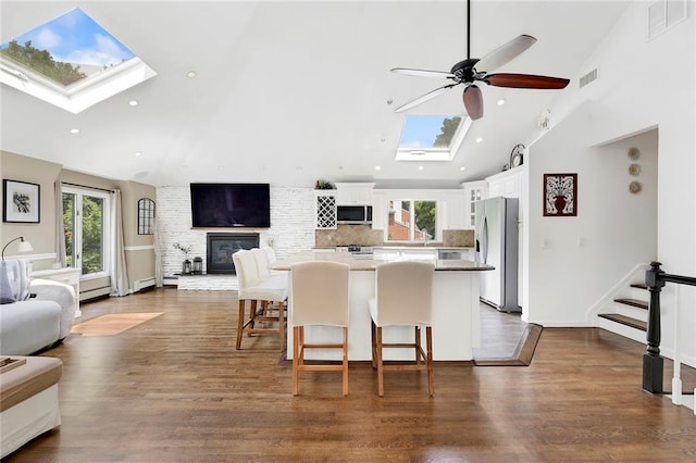 kitchen featuring high vaulted ceiling, a center island, stainless steel appliances, open floor plan, and a skylight