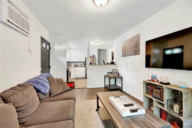 living area with a wall mounted air conditioner, baseboards, and wood finished floors