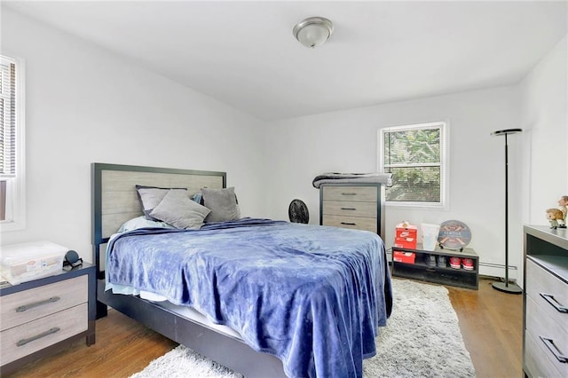 bedroom with a baseboard heating unit and wood finished floors
