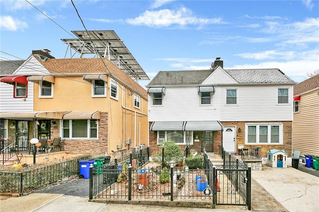 view of property featuring a fenced front yard, a chimney, and concrete driveway