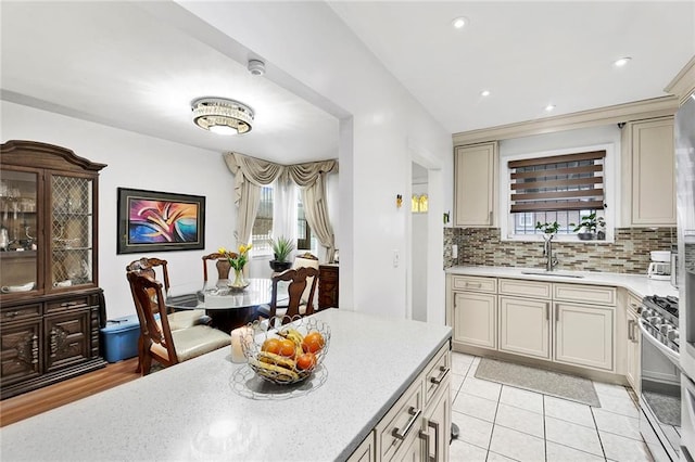 kitchen with backsplash, stainless steel range with gas stovetop, recessed lighting, light tile patterned flooring, and a sink