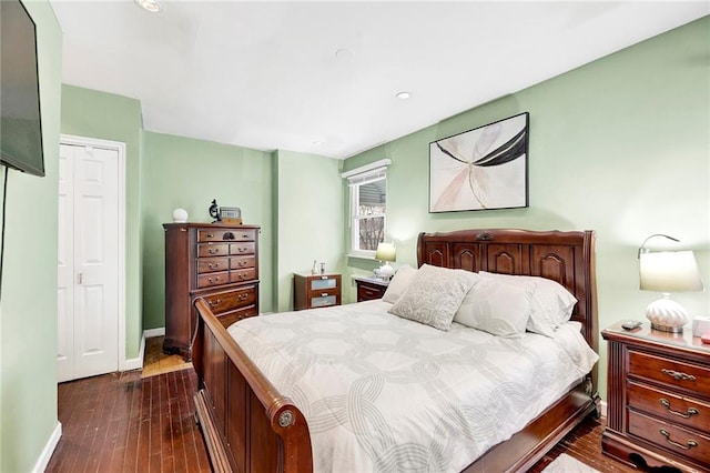 bedroom with a closet, baseboards, and dark wood-style flooring