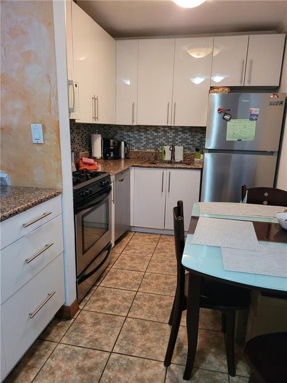 kitchen featuring light tile patterned floors, appliances with stainless steel finishes, and white cabinetry