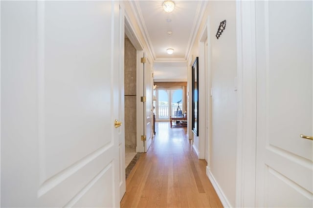 hall featuring baseboards, light wood-style flooring, and crown molding