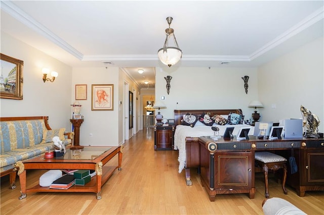 living room with visible vents, a raised ceiling, light wood-style floors, and crown molding