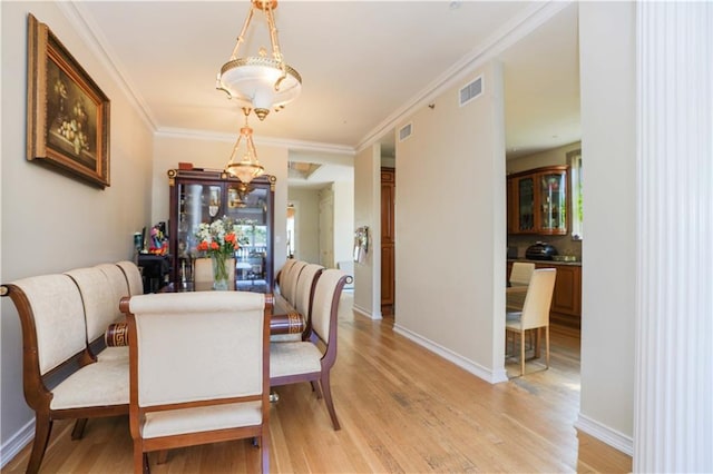 dining space with visible vents, light wood-style flooring, and crown molding