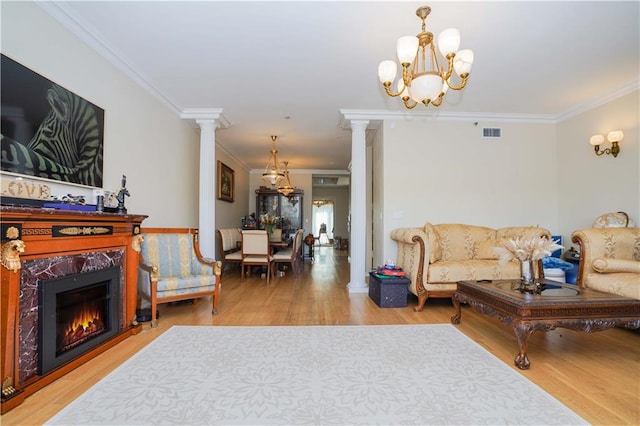 living room with light wood-type flooring, decorative columns, visible vents, and a high end fireplace