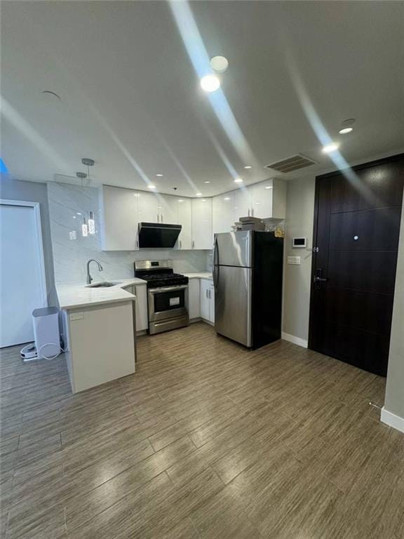 kitchen featuring a sink, stainless steel appliances, light countertops, a peninsula, and visible vents
