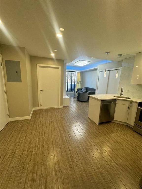 kitchen with light countertops, dishwasher, a sink, electric panel, and open floor plan