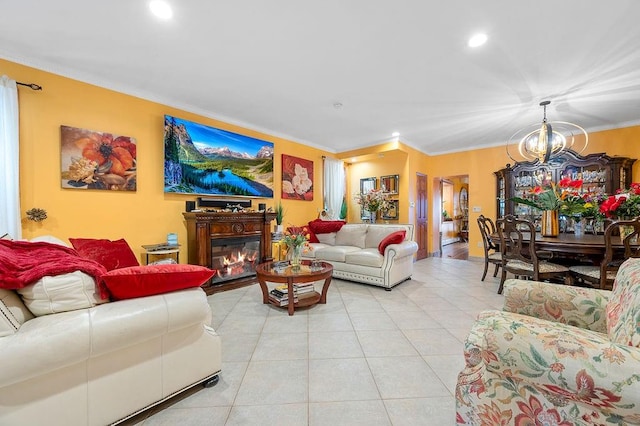 living area featuring crown molding, a chandelier, recessed lighting, light tile patterned flooring, and a glass covered fireplace