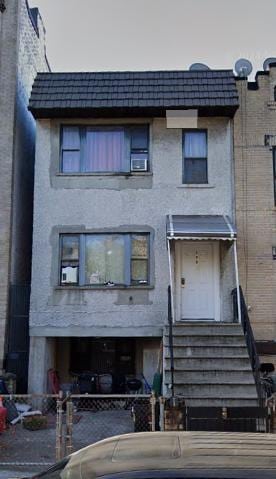 back of property featuring a fenced front yard and mansard roof