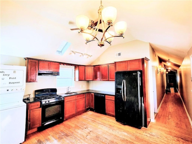 kitchen featuring visible vents, stacked washing maching and dryer, an inviting chandelier, black appliances, and under cabinet range hood