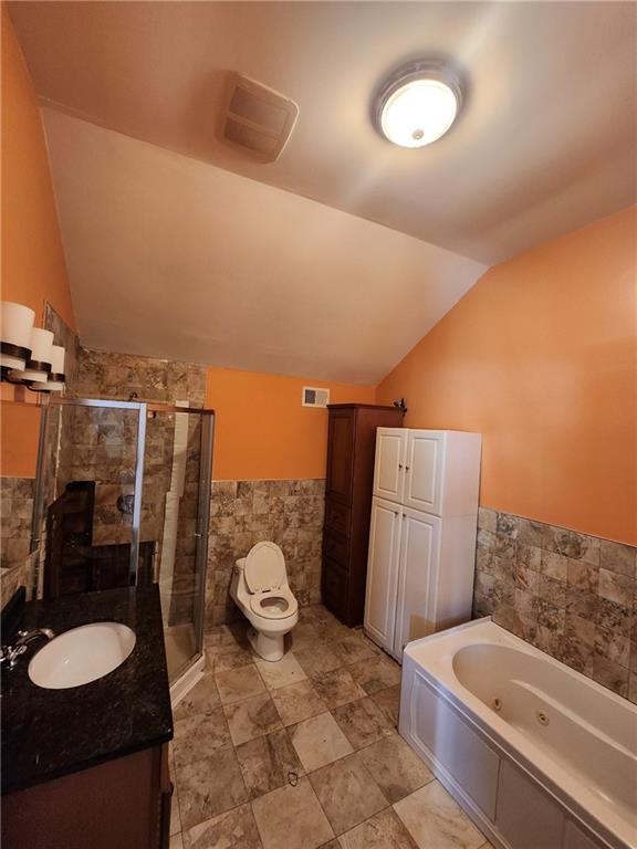 full bath featuring visible vents, lofted ceiling, a stall shower, tile walls, and a jetted tub