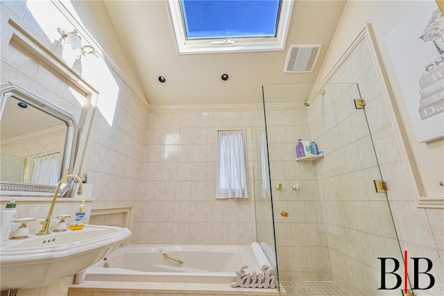 bathroom with visible vents, a shower stall, a bath, tile walls, and a sink