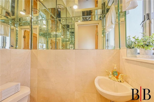 bathroom featuring tile walls, toilet, and a sink