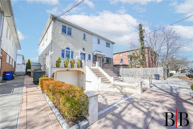 townhome / multi-family property featuring stucco siding, an attached garage, stairs, and fence