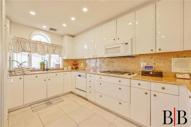 kitchen featuring white appliances, visible vents, a sink, white cabinetry, and tasteful backsplash