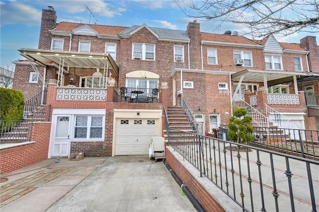 view of front of house featuring brick siding, fence, stairway, concrete driveway, and a chimney