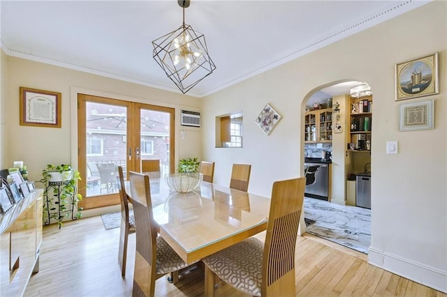dining area featuring crown molding, arched walkways, and light wood-type flooring