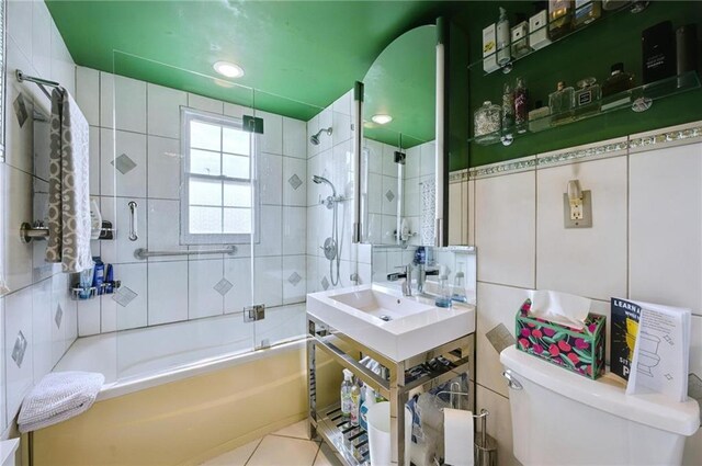 full bathroom featuring tile walls, tile patterned flooring, vanity, combined bath / shower with glass door, and toilet