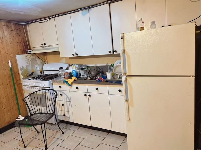 368 54th St, Brooklyn, NY 11220 - kitchen with white appliances, under cabinet range hood, white cabinets, light tile patterned flooring, and dark countertops