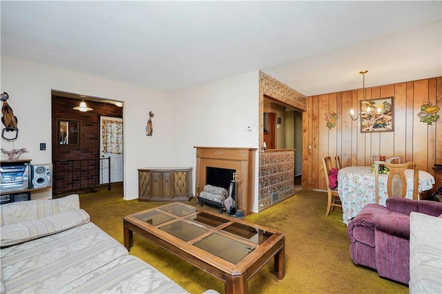 carpeted living room featuring wood walls, a fireplace, and an inviting chandelier