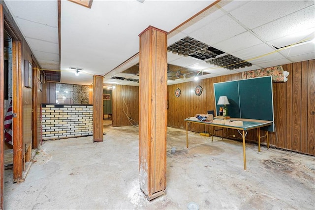 finished basement featuring a drop ceiling and wood walls