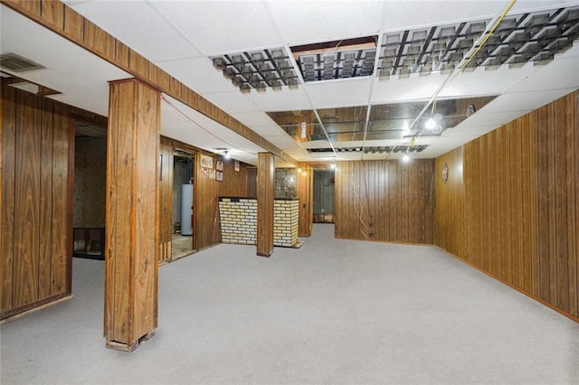 finished basement featuring wooden walls, carpet flooring, and water heater