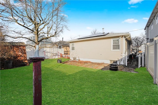 back of property featuring a fenced backyard, roof mounted solar panels, and a yard