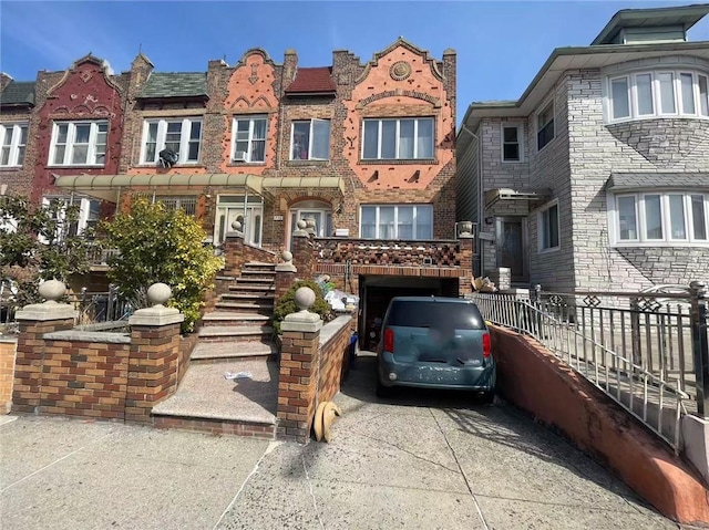 view of front of house featuring brick siding, driveway, and fence