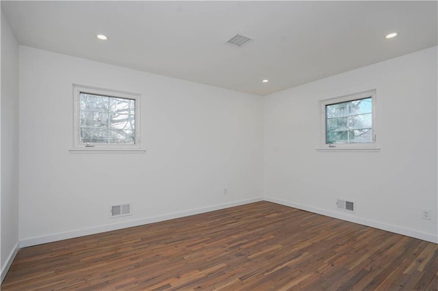 unfurnished room with dark wood-type flooring and visible vents