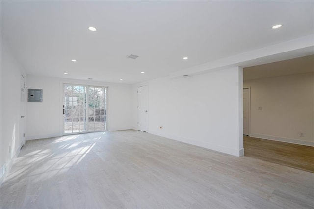 empty room featuring electric panel, recessed lighting, light wood-type flooring, and baseboards