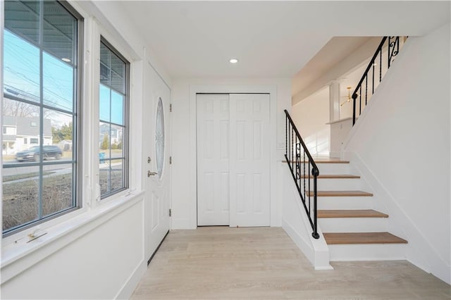 foyer featuring recessed lighting, stairway, baseboards, and light wood-style floors