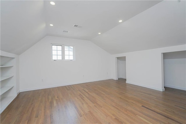 bonus room with baseboards, built in shelves, wood finished floors, and vaulted ceiling