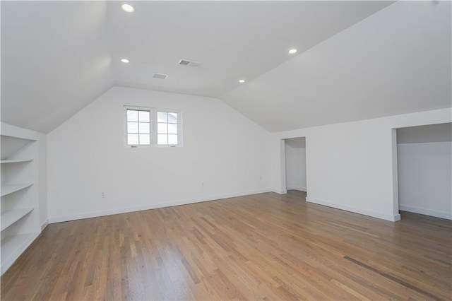 additional living space with recessed lighting, built in shelves, wood finished floors, and vaulted ceiling