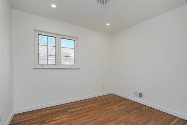 empty room featuring wood finished floors, recessed lighting, baseboards, and visible vents