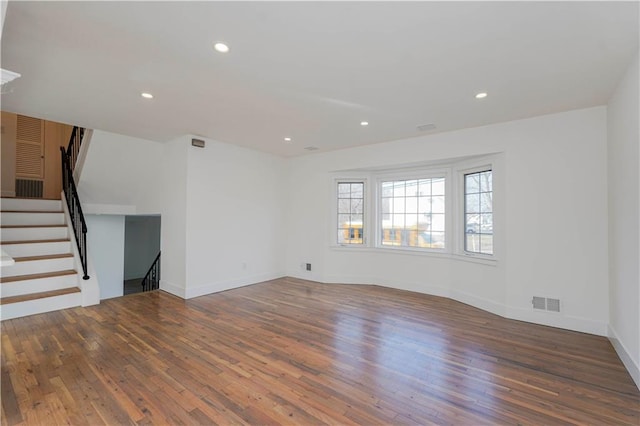 unfurnished living room featuring visible vents, wood finished floors, recessed lighting, stairway, and baseboards