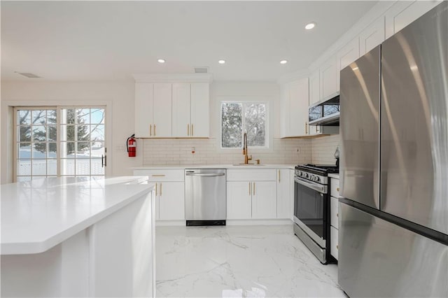 kitchen with recessed lighting, a sink, appliances with stainless steel finishes, marble finish floor, and backsplash