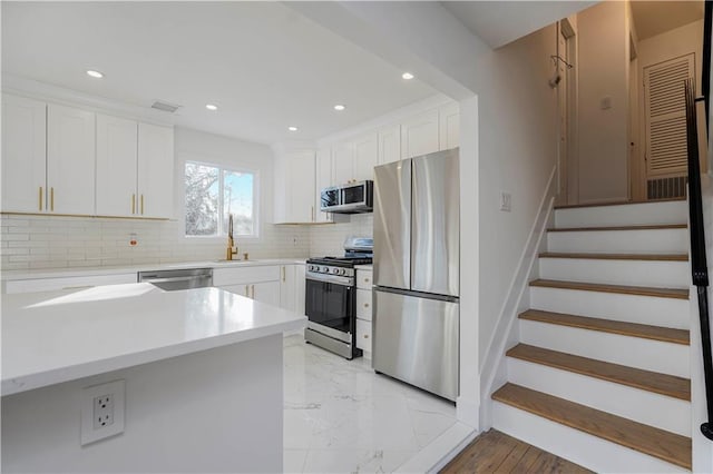 kitchen with decorative backsplash, white cabinets, appliances with stainless steel finishes, and a sink