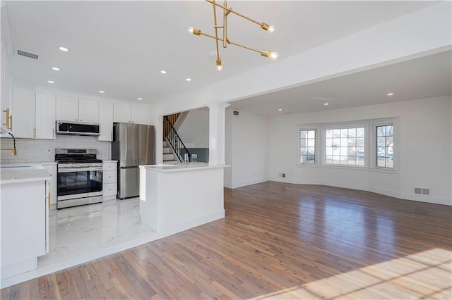 kitchen with stainless steel appliances, backsplash, visible vents, and open floor plan