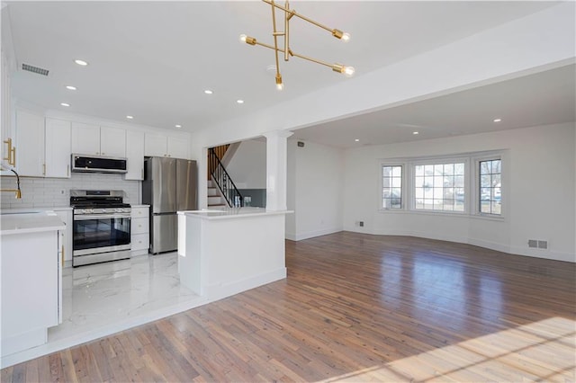 kitchen with open floor plan, tasteful backsplash, visible vents, and stainless steel appliances