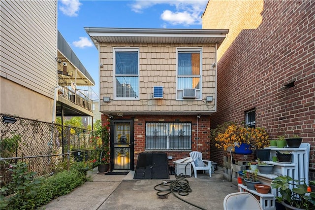 back of house featuring mansard roof, a patio, brick siding, and fence