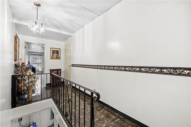 hallway with an upstairs landing and a chandelier