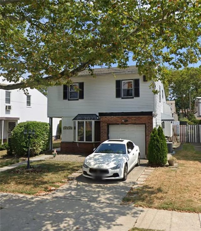 view of front facade with brick siding, concrete driveway, an attached garage, and fence