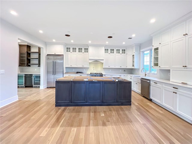 kitchen with wood counters, wine cooler, appliances with stainless steel finishes, and white cabinets