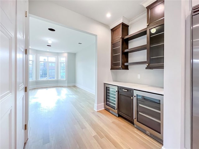 bar featuring baseboards, a bar, beverage cooler, and light wood finished floors