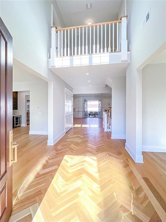 foyer entrance with visible vents, baseboards, and a high ceiling