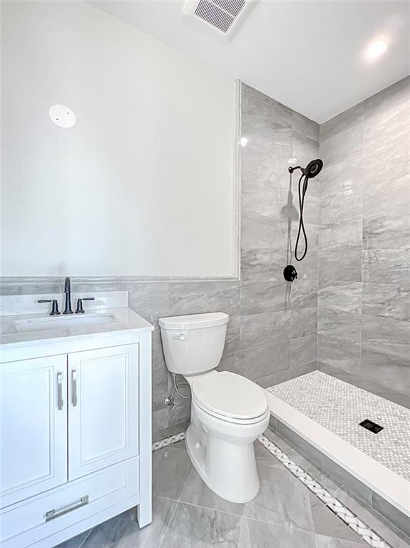 859 Lamont Ave, Staten Island, NY 10309 - bathroom with a tile shower, toilet, vanity, wainscoting, and tile walls