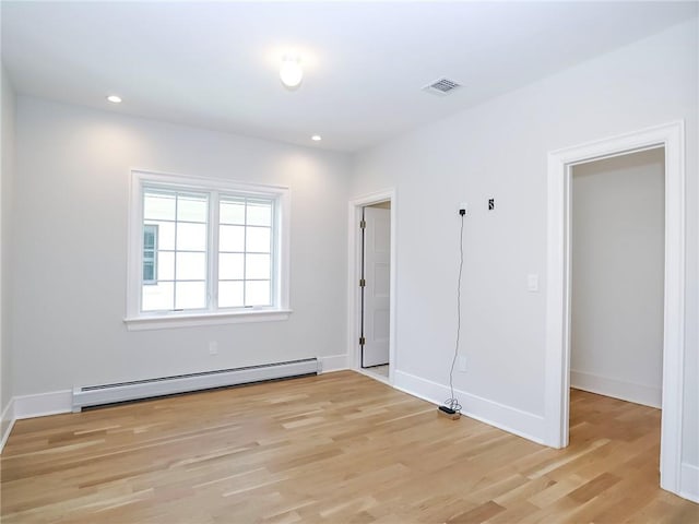 empty room with a baseboard heating unit, recessed lighting, visible vents, and light wood-type flooring