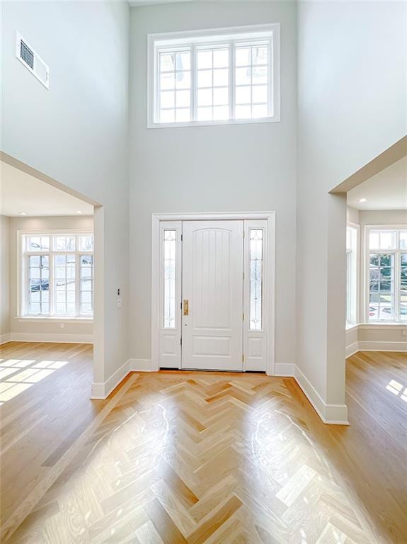 foyer featuring visible vents, baseboards, and a towering ceiling